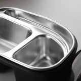 Close-up of a stainless steel three-compartment divided lunch tray with a black outer base, shown on a neutral gray background.