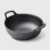 A black cast iron kadhai pot with two loop handles, photographed on a clean light gray background.