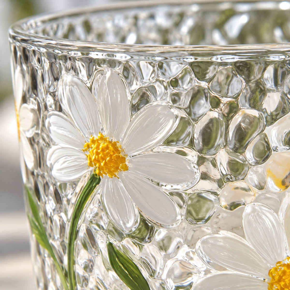 A close-up of the Hammered Daisy Glass Cup shows its dimpled glass and painted daisy detail.
