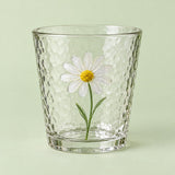 The short Hammered Daisy Glass Cup is shown alone against a pale green studio backdrop.
