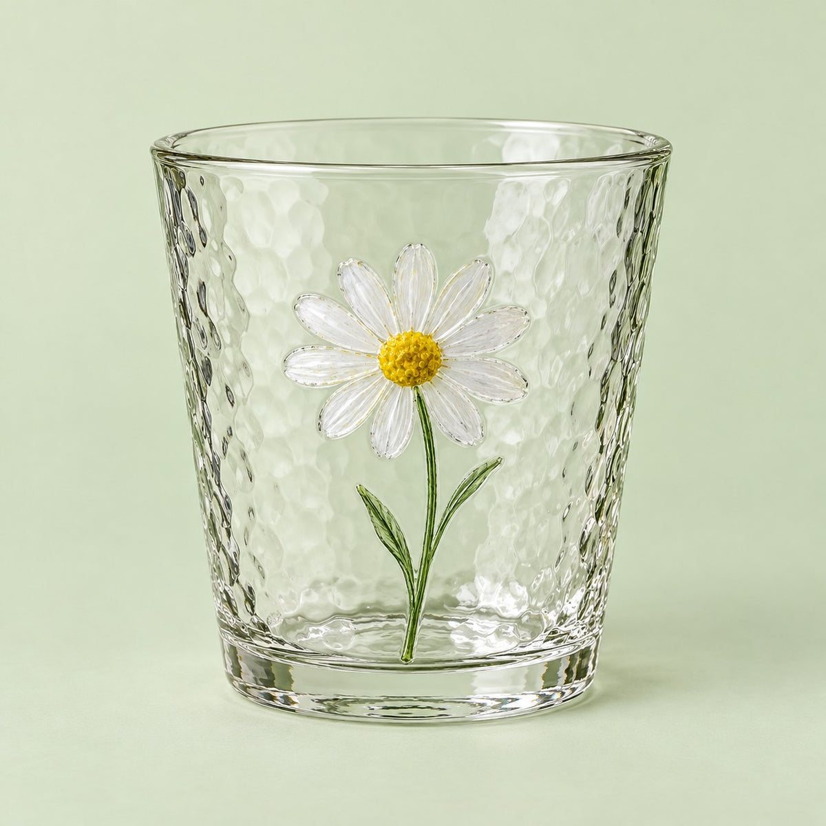 The short Hammered Daisy Glass Cup is shown alone against a pale green studio backdrop.