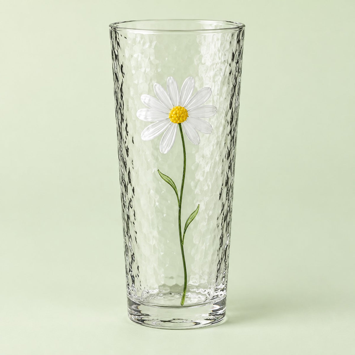 The tall Hammered Daisy Glass Cup is shown alone against a pale green studio backdrop.