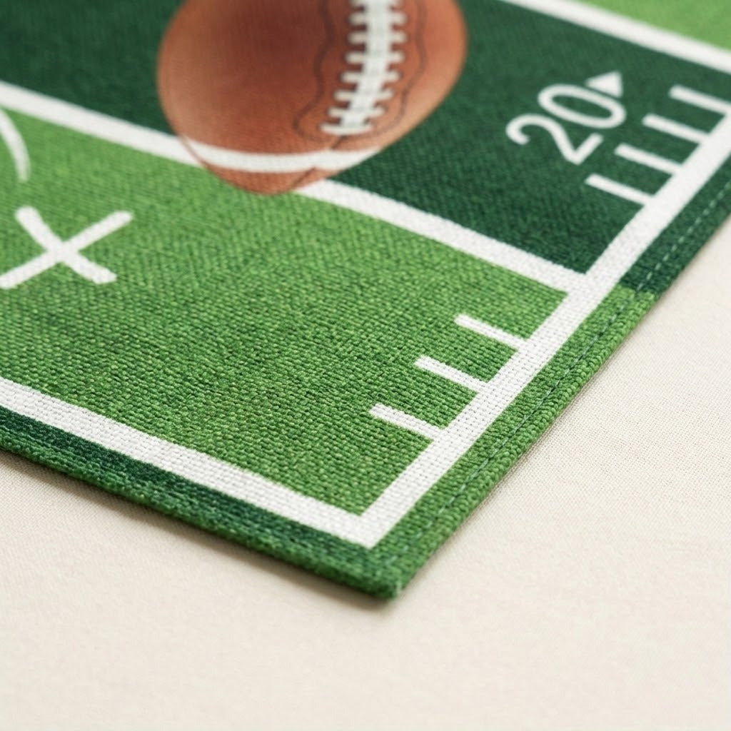 A close-up of a green football field printed rug or mat with white yard line markings, a brown football graphic, and the number 20, shown on a light beige surface.