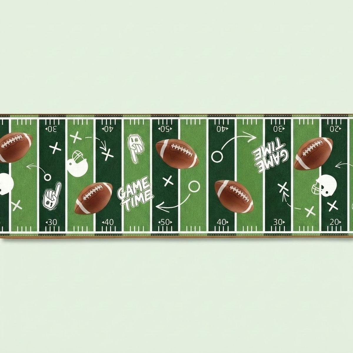 A horizontal strip of sports wall decal featuring a green football field design with white yard lines, brown footballs, white helmets, and the words 'GAME TIME' on a pale mint background.