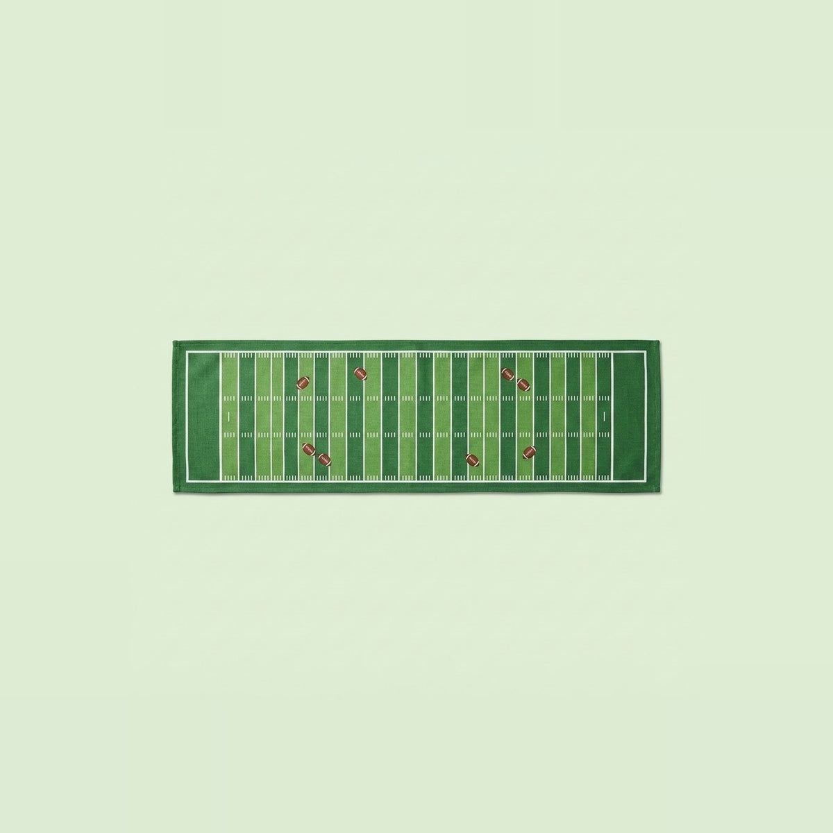 A rectangular green towel featuring a football field design with yard lines and small red accents, displayed flat against a pale green background.