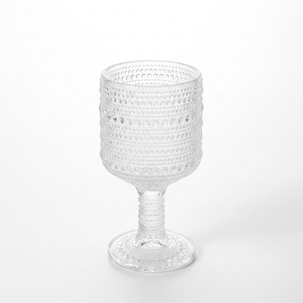 A clear textured glass goblet with a beaded bubble pattern, set against a seamless white background.