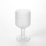 A clear textured glass goblet with a beaded bubble pattern, set against a seamless white background.