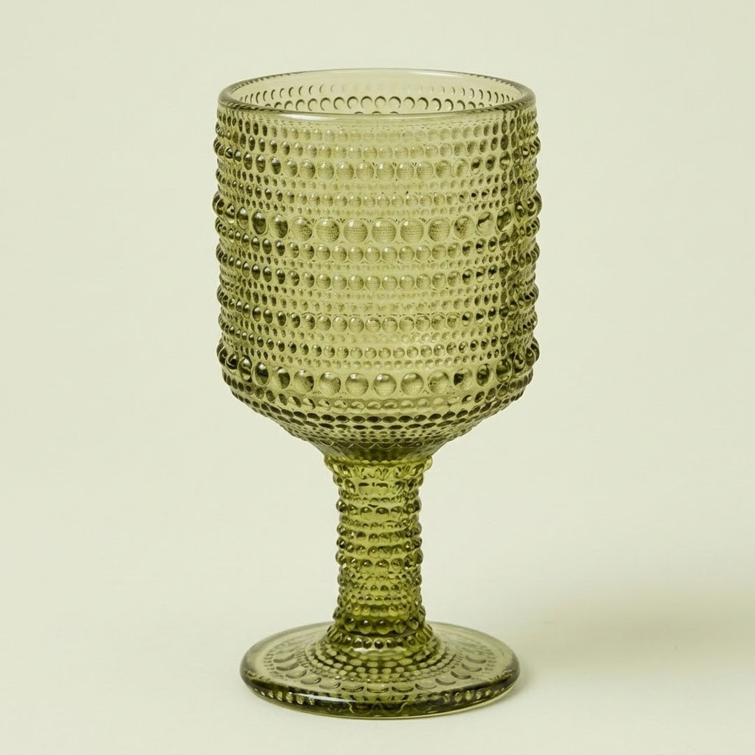 An olive green glass goblet with a textured, beaded pattern on the bowl and stem, set against a plain off-white background.