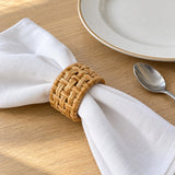 Natural rattan napkin ring beside a dinner plate and spoon shows its everyday scale.