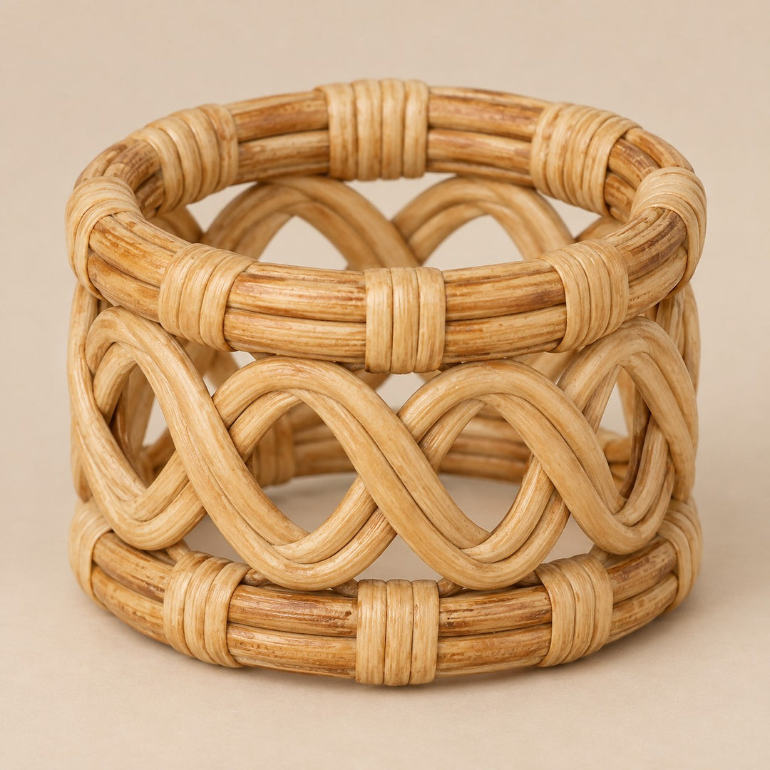 Natural open braid rattan napkin ring shown alone against a pale tan backdrop.