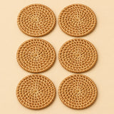 Set of six round rattan coasters arranged together on a soft beige studio background.