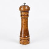 A classic wooden pepper mill with a warm brown wood grain finish and a small silver metal top knob, set against a plain white background.