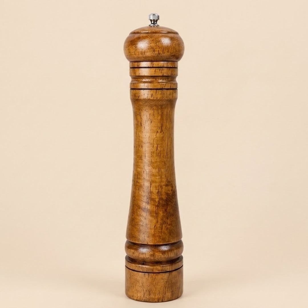 A tall wooden pepper mill with a polished medium-brown wood finish and a small silver metal top knob, set against a solid beige background.