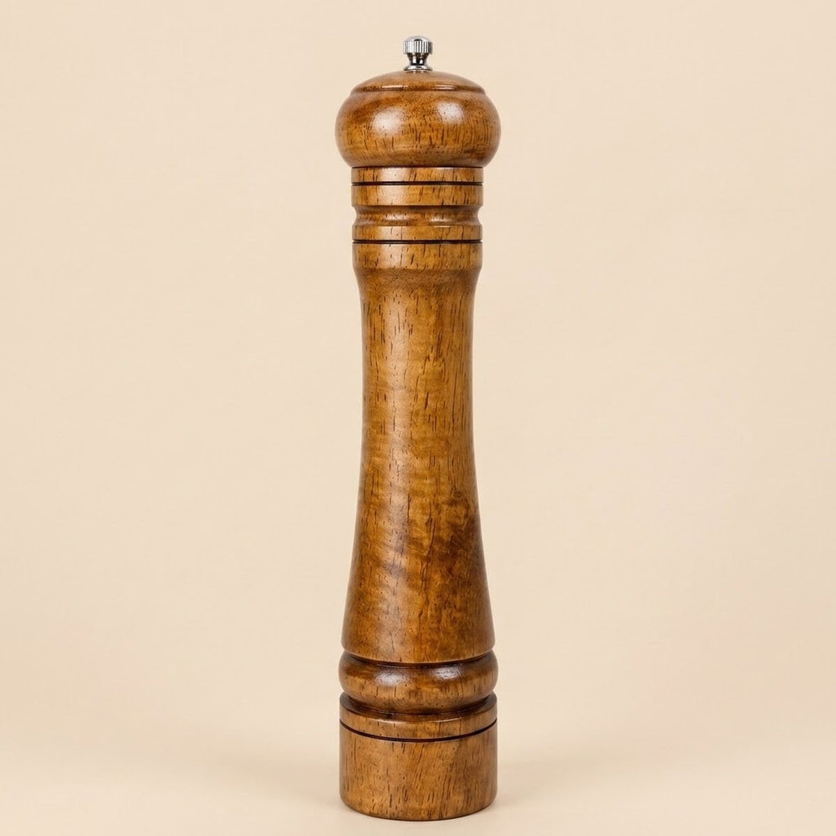 A tall wooden pepper mill with a polished medium-brown wood finish and a small silver metal top knob, set against a solid beige background.