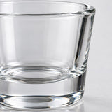 A macro view shows the smooth clear glass, polished rim, and thick base of a shot glass.