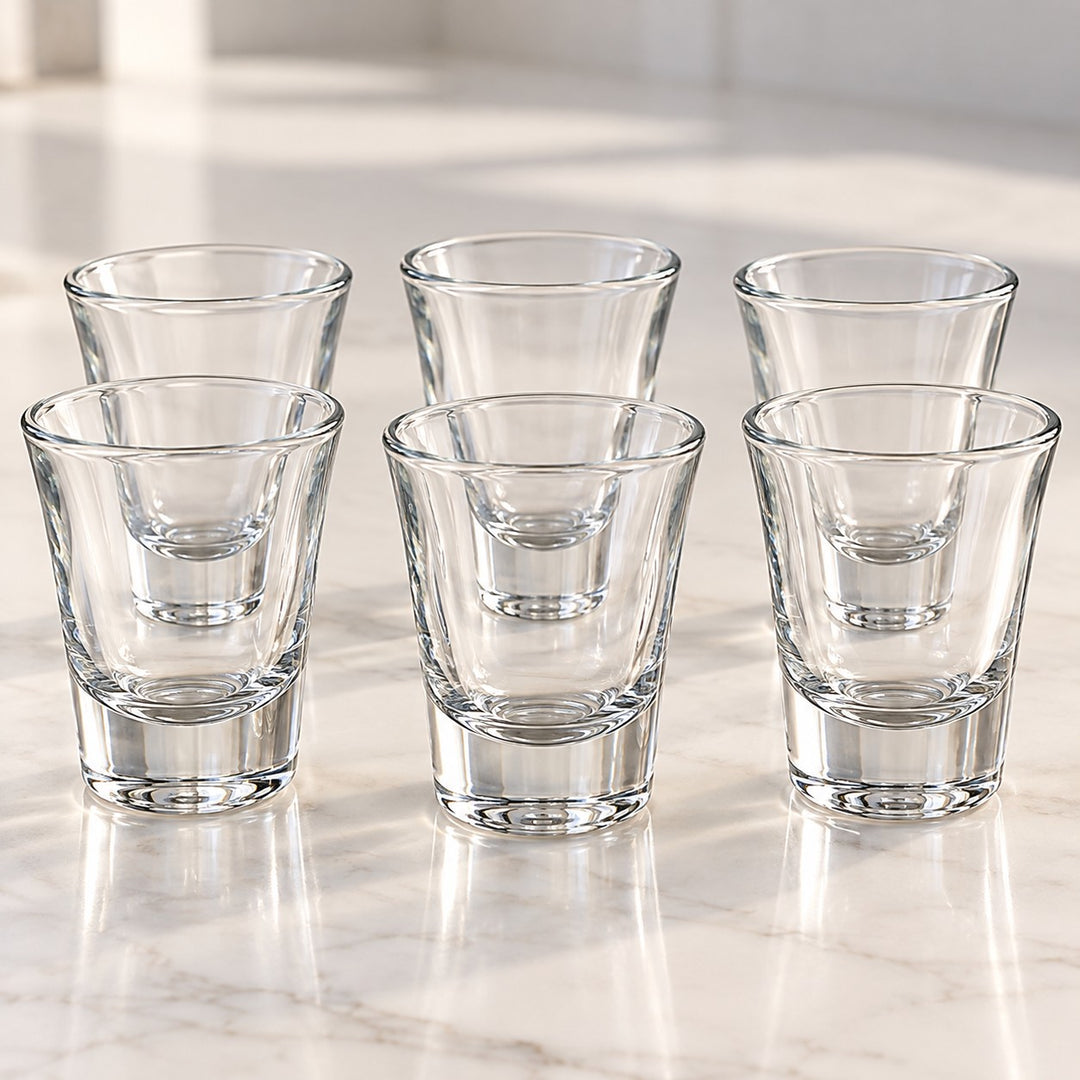 Six clear tapered shot glasses show their transparent walls and thick, sturdy bases.