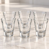 Six clear tapered shot glasses show their transparent walls and thick, sturdy bases.
