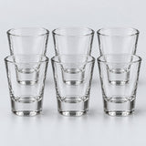 Six tapered clear glass shot glasses form the Tapered style set against a pale backdrop.