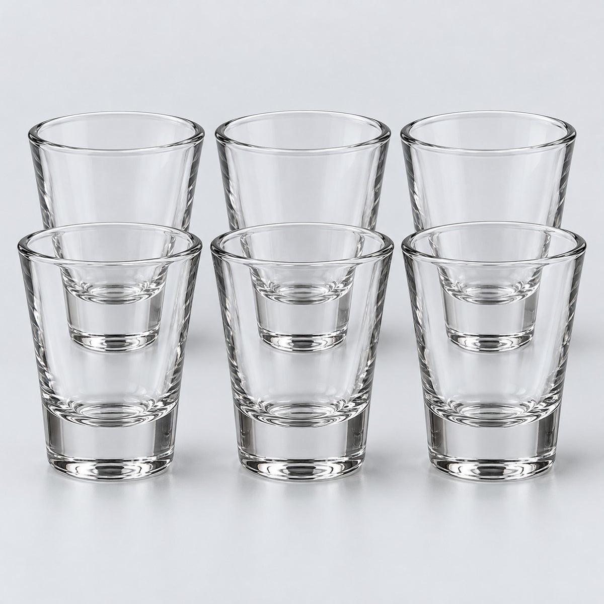 Six tapered clear glass shot glasses form the Tapered style set against a pale backdrop.