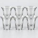 Six clear shot glasses with flared rims show the Flared Rim style on a pale backdrop.