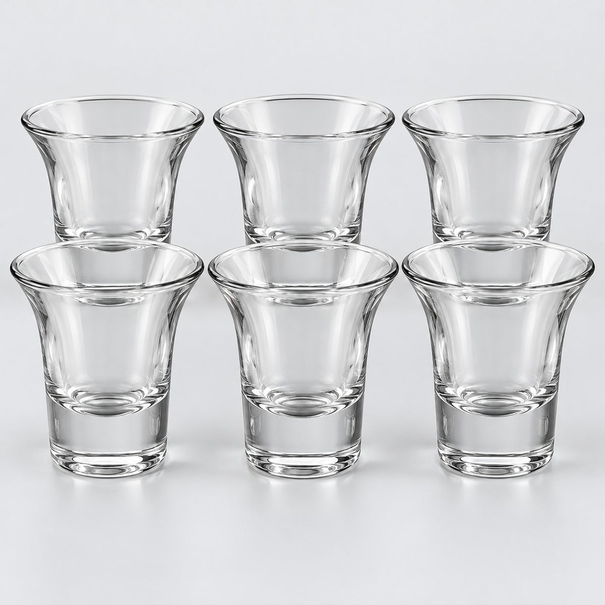 Six clear shot glasses with flared rims show the Flared Rim style on a pale backdrop.
