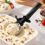 Ice cream scoop shapes a serving from a tub on a bright kitchen counter.
