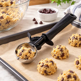 Ice cream and cookie scoop portions dough onto a baking tray in a home kitchen.