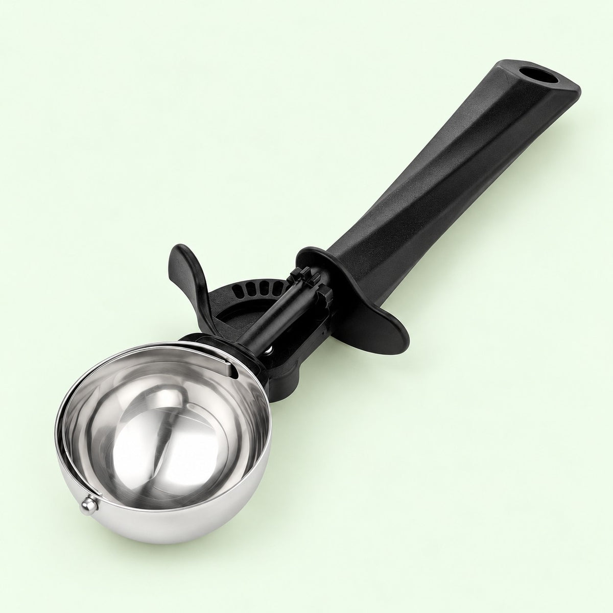 Largest ice cream scoop with polished steel bowl and black handle on a pale green backdrop.