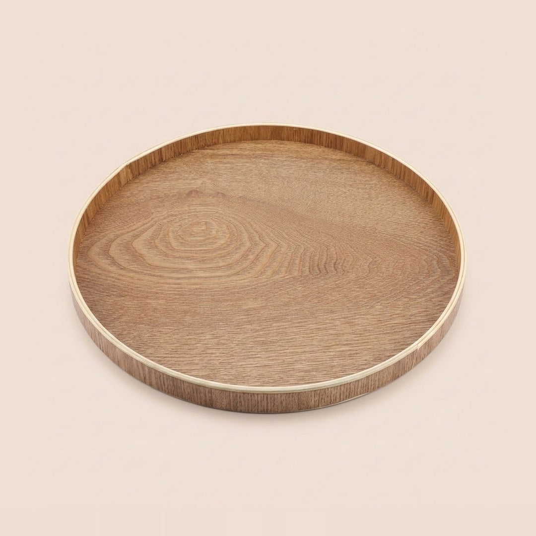 A round wooden serving tray with a natural oak grain pattern and a light-colored rim, shown on a solid beige background.