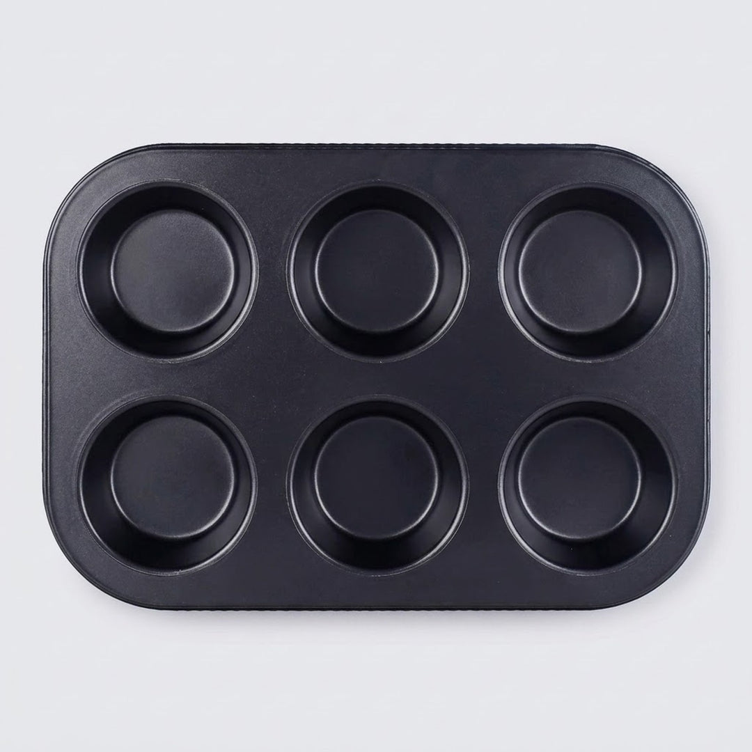 A black non-stick six-cup muffin tin with a rectangular base and six round cups, photographed from directly above on a light gray background.