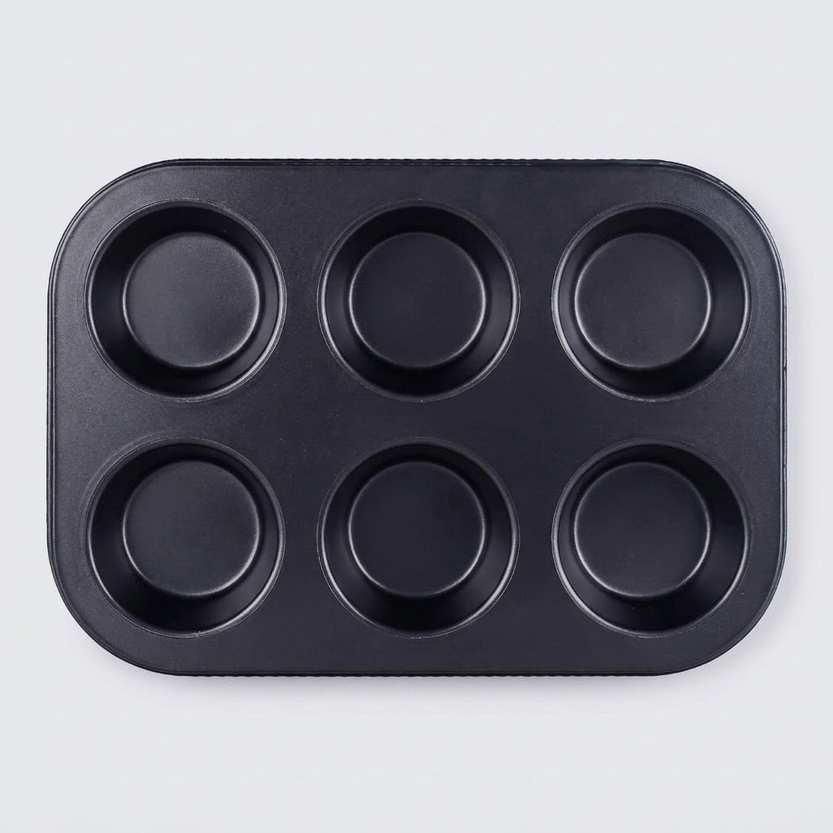 A black non-stick six-cup muffin tin with a rectangular base and six round cups, photographed from directly above on a light gray background.