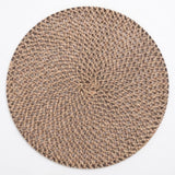 A round braided placemat with a textured woven pattern in shades of brown and beige, shown flat against a white background.