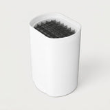 A white cylindrical device with a slanted top opening, featuring a dark gray honeycomb filter or mesh insert visible inside, set against a plain light gray background.
