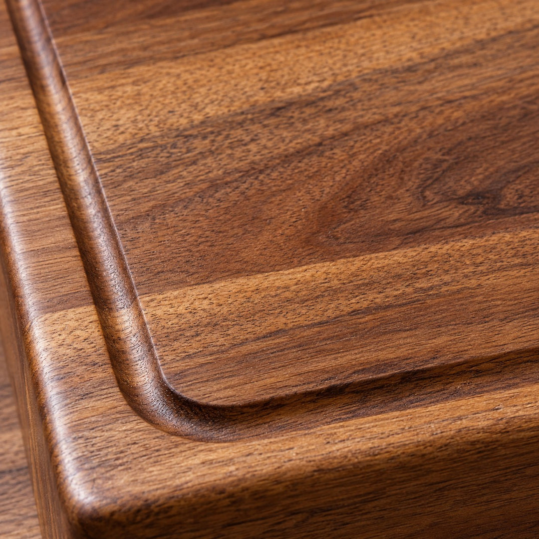 A macro view of the wood cutting board reveals its warm grain, smooth finish, and carved groove.