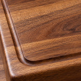 A macro view of the wood cutting board reveals its warm grain, smooth finish, and carved groove.