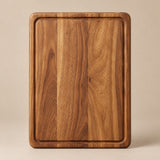 The small rectangular wood cutting board is centered on a pale tan studio background.
