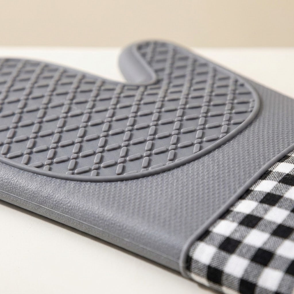A gray silicone oven mitt with a textured non-slip grip and a black-and-white gingham checkered fabric wrist strap, shown on a light beige background.