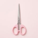 Pink-handled scissors with silver metal blades, centered on a solid pale pink background.