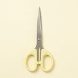 A pair of scissors with pale yellow handles and silver metal blades, centered on a solid cream-colored background.