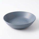 A matte slate blue ceramic bowl photographed from a high angle on a clean white background.