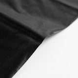 A close-up of a black material, likely leather or faux leather, draped diagonally across a plain white surface.
