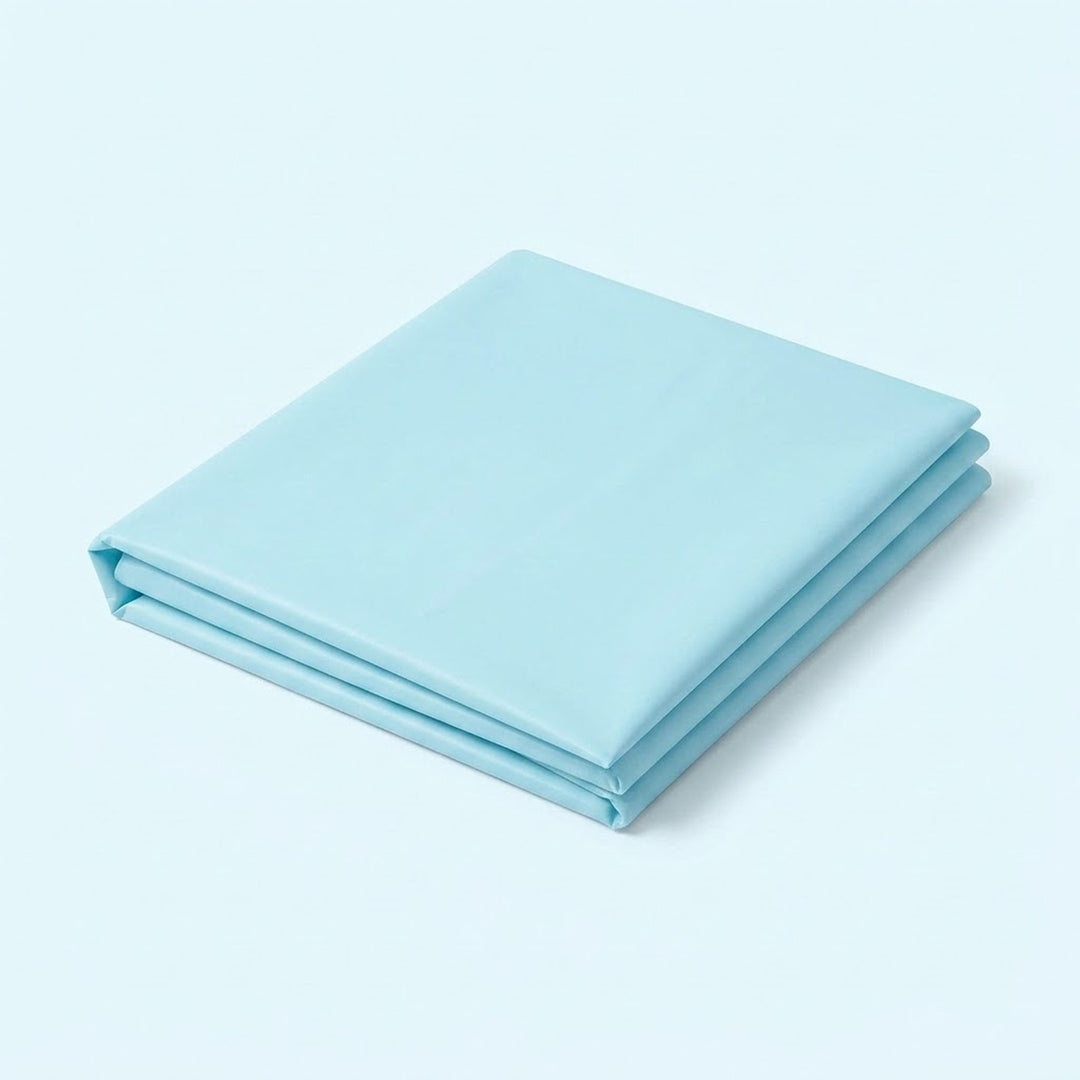 A folded light blue fabric sheet or bedding piece, neatly stacked on a clean, solid light blue background.