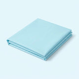 A folded light blue fabric sheet or bedding piece, neatly stacked on a clean, solid light blue background.