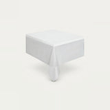 A white square tablecloth draped over a table, shown from an elevated angle against a clean, off-white background.