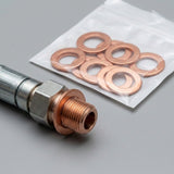 A close-up of a metal pipe fitting with a copper thread, shown next to a clear plastic bag containing several copper washers on a gray background.