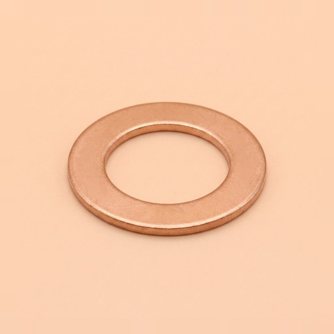 A single flat metal washer with a warm copper or rose-gold metallic finish, centered on a solid peach-beige background.
