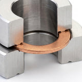 Close-up of a metallic U-shaped silver clamp holding a copper-colored ring against a white background.
