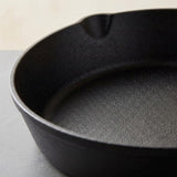 Close-up of a black cast iron skillet showing the textured interior and a small pouring lip on the rim.