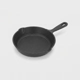 A classic black cast iron skillet with a single loop handle, photographed on a clean, light gray studio background.