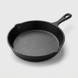 A classic black cast iron skillet with a single loop handle, photographed from a high angle on a light gray background.